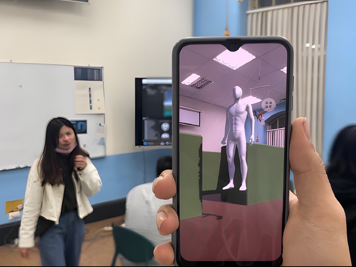 A phone held in hand showing the AR scene anchored on the classroom floor, a humanoid companion model standing in front of a wall.