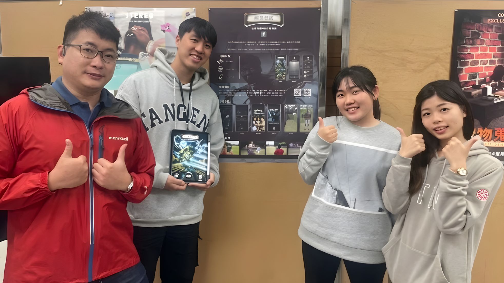 Four students standing in front of the 榕易迷路 exhibition poster, smiling with thumbs up. One holds a tablet showing the app.