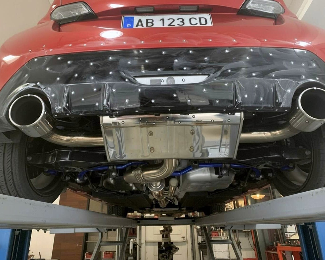 Photogrammetry tracking dots applied to the rear of a red car for 3D scanning.