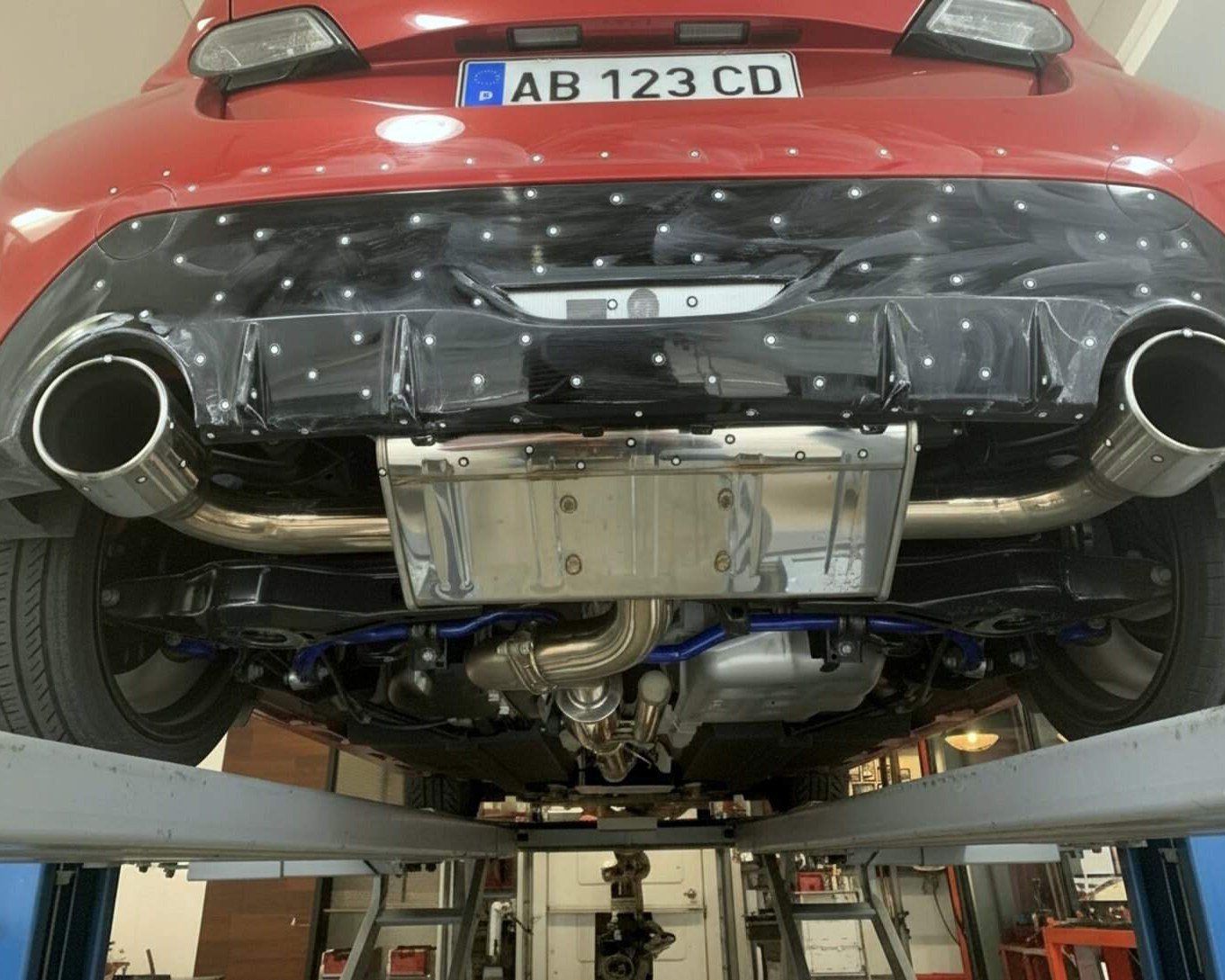 Photogrammetry tracking dots applied to the rear of a red car for 3D scanning.