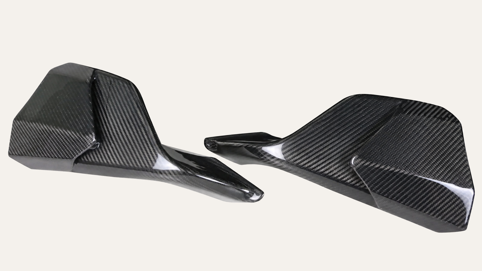 Two carbon-fiber aero components with their woven surface and curved edges visible.