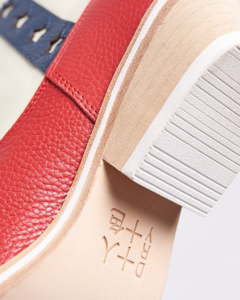 Flag Boots: a pair of red-white-and-blue color-block Western ankle boots with white star embroidery on the heel cup and a contrast tonal striped sole, photographed on white.
