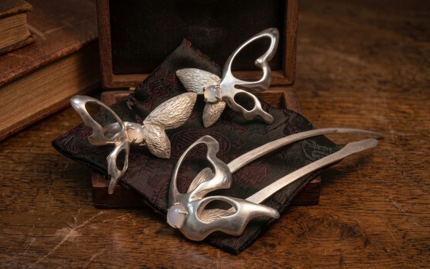 Liang-Zhu jewelry set — butterfly hairpin and brooches arranged on dark wood with a leather book.